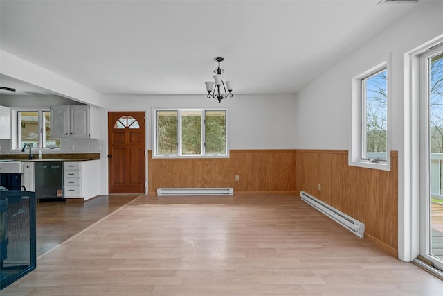 242 Callicoon Center Rd, Jeffersonville, NY 12748 - unfurnished dining area with a baseboard heating unit, baseboard heating, light wood finished floors, a notable chandelier, and wainscoting