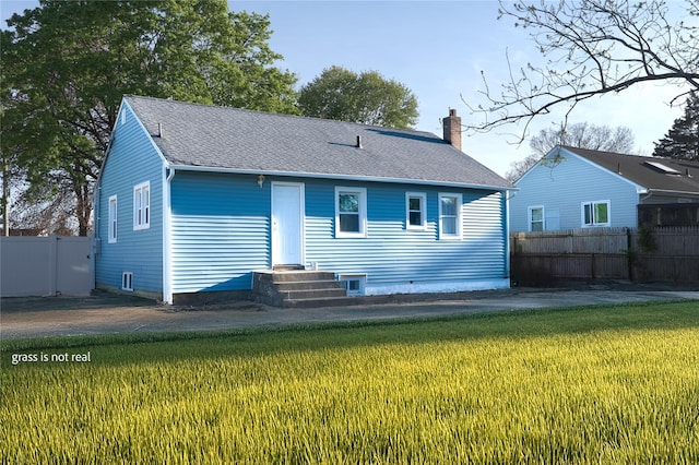 23 Cumberbach St, Wyandanch, NY 11798 - back of property with a lawn, fence, a chimney, and roof with shingles