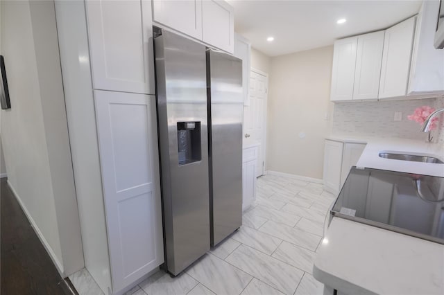 23 Cumberbach St, Wyandanch, NY 11798 - kitchen with baseboards, stainless steel fridge, white cabinetry, a sink, and backsplash