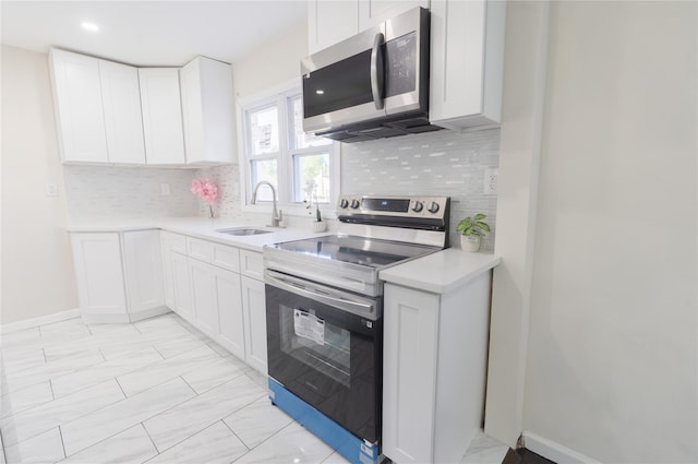 23 Cumberbach St, Wyandanch, NY 11798 - kitchen featuring decorative backsplash, light countertops, white cabinetry, a sink, and appliances with stainless steel finishes