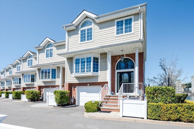 townhome / multi-family property with driveway, brick siding, and a garage