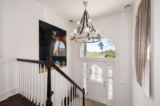 foyer entrance with baseboards, visible vents, and an inviting chandelier