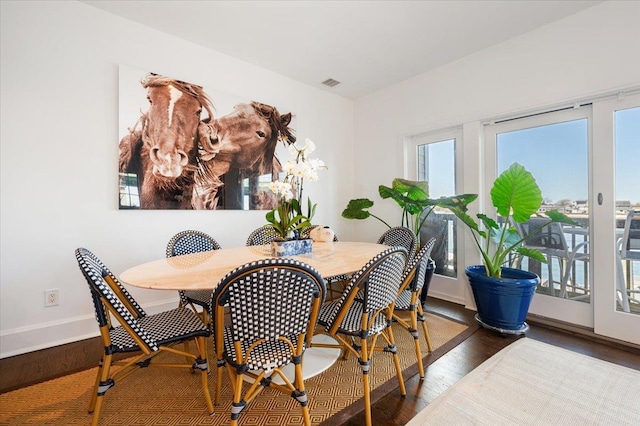 dining area featuring baseboards, wood finished floors, and visible vents