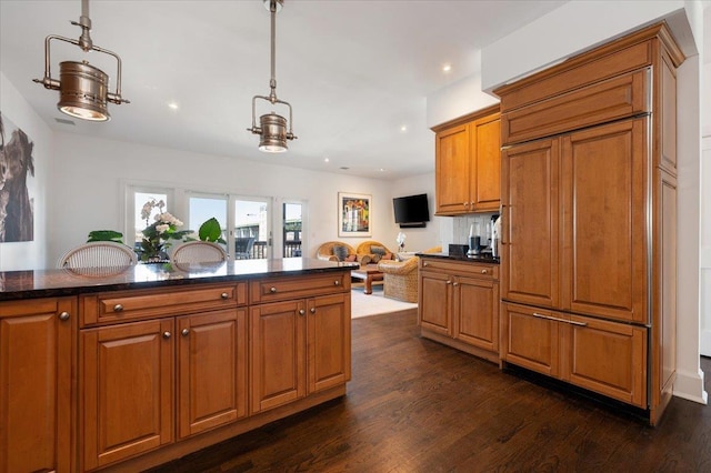 kitchen with brown cabinetry, open floor plan, decorative light fixtures, dark wood finished floors, and recessed lighting