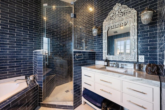 bathroom featuring a tile shower, tile walls, a garden tub, and vanity