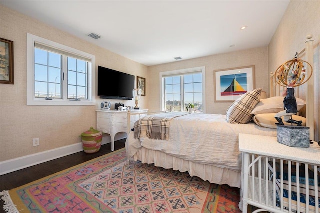 bedroom with baseboards, wood finished floors, and visible vents