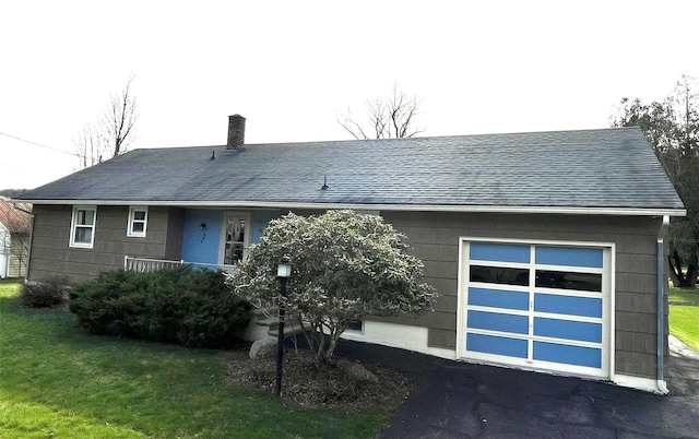 view of front facade featuring driveway, roof with shingles, a front yard, and a garage