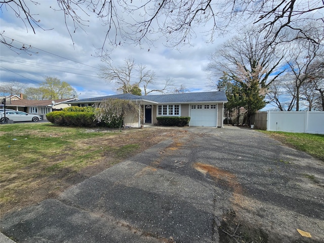 ranch-style house with fence, an attached garage, and aphalt driveway