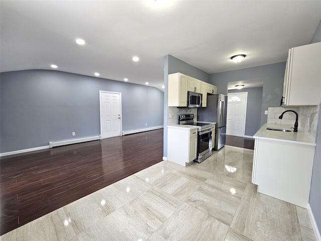 kitchen with a sink, light countertops, backsplash, baseboards, and appliances with stainless steel finishes