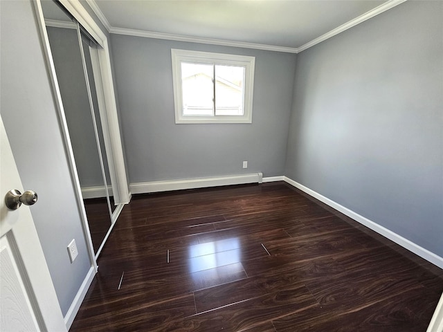 unfurnished bedroom featuring dark wood finished floors, a baseboard radiator, a closet, ornamental molding, and baseboards