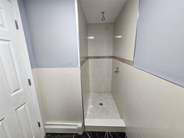 bathroom with baseboard heating, tiled shower, and wainscoting