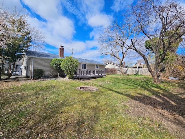 view of yard with fence, a fire pit, and a deck