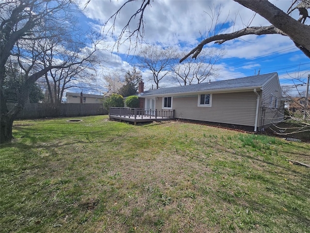 back of property with a lawn, a deck, and a fenced backyard