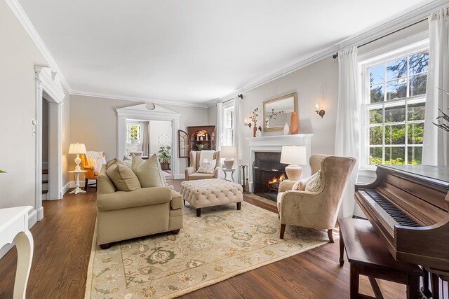 living room with a fireplace with flush hearth, crown molding, wood finished floors, and baseboards