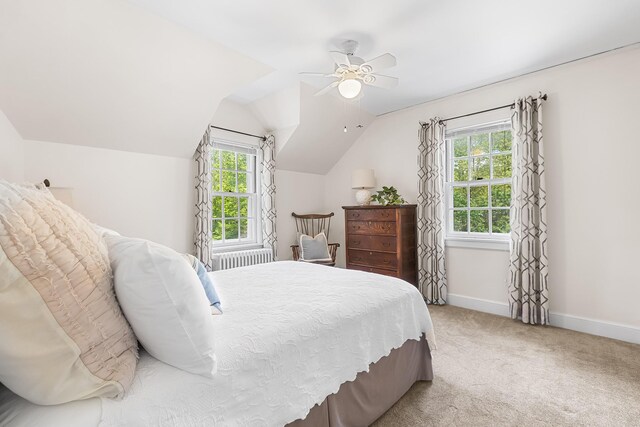 bedroom featuring multiple windows, baseboards, light colored carpet, vaulted ceiling, and ceiling fan