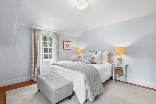 bedroom with vaulted ceiling, baseboards, and wood finished floors