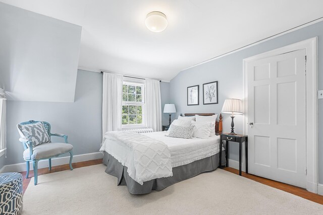 bedroom featuring wood finished floors, baseboards, vaulted ceiling, and crown molding