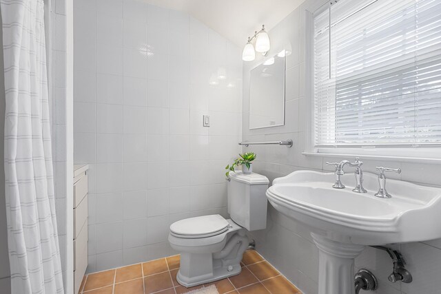 bathroom featuring tile patterned flooring, toilet, tile walls, vaulted ceiling, and a shower with curtain