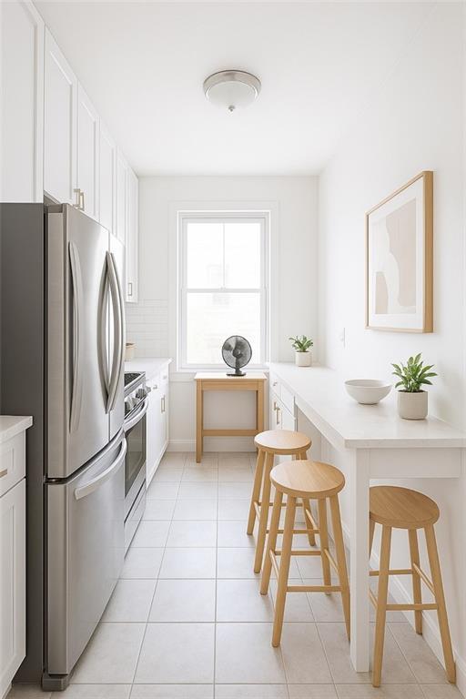 86-03 102nd St Unit 2D, Richmond Hill, NY 11418 - kitchen with light tile patterned flooring, a breakfast bar, stainless steel appliances, light countertops, and white cabinetry