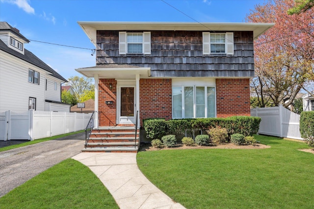 view of front of home featuring fence, a front yard, and brick siding