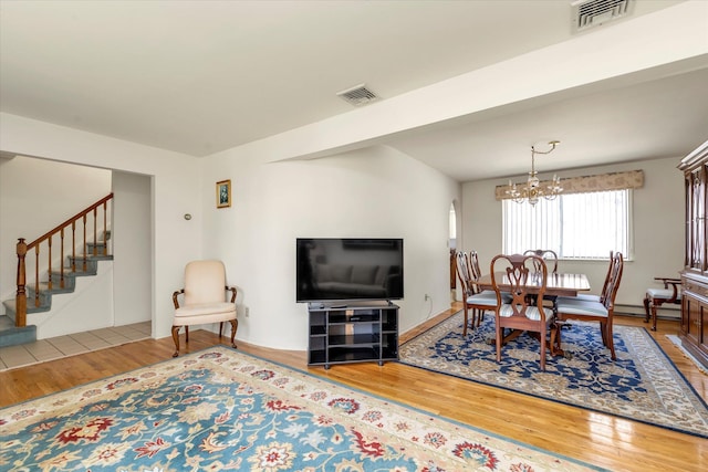 living room featuring stairs, visible vents, and wood finished floors