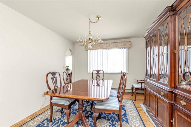 dining area with light wood-style floors, arched walkways, baseboards, and a chandelier