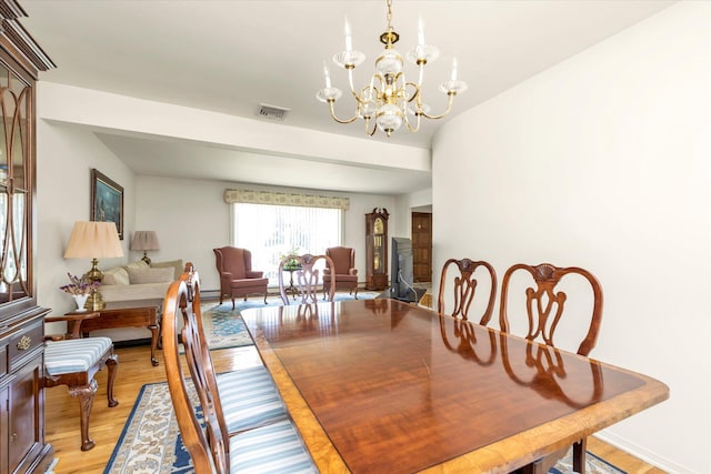 dining room with light wood-type flooring, baseboards, a chandelier, and visible vents