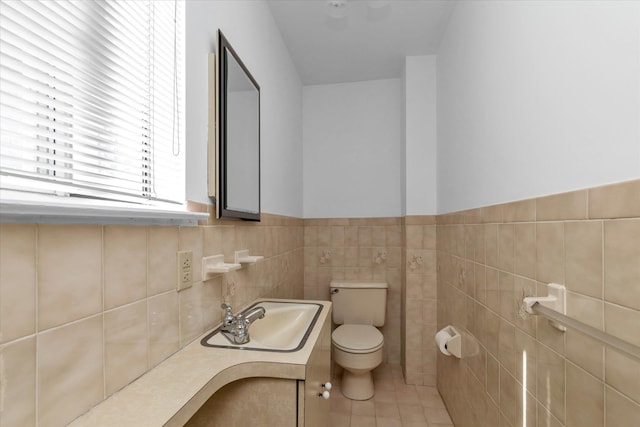 bathroom with tile walls, tile patterned floors, a wainscoted wall, vanity, and toilet
