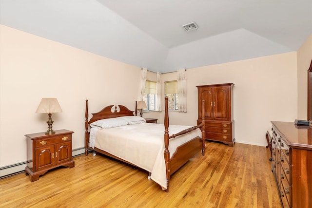bedroom featuring a baseboard heating unit, visible vents, light wood-style flooring, and vaulted ceiling
