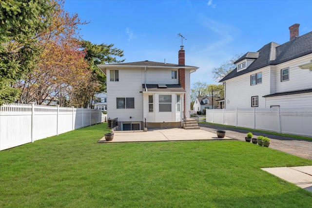rear view of property with a lawn, a fenced backyard, a patio area, and a chimney