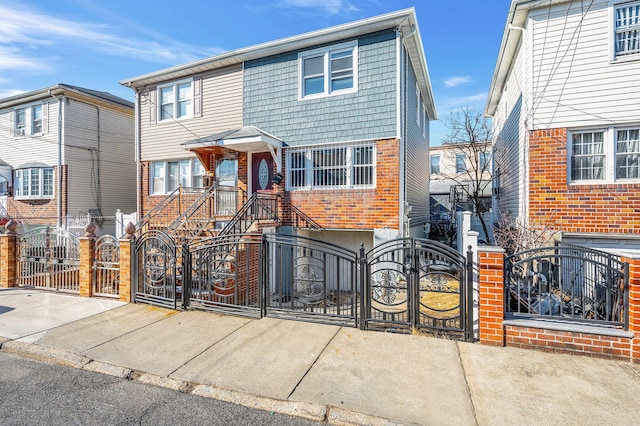 view of front facade featuring a gate, brick siding, concrete driveway, and a fenced front yard