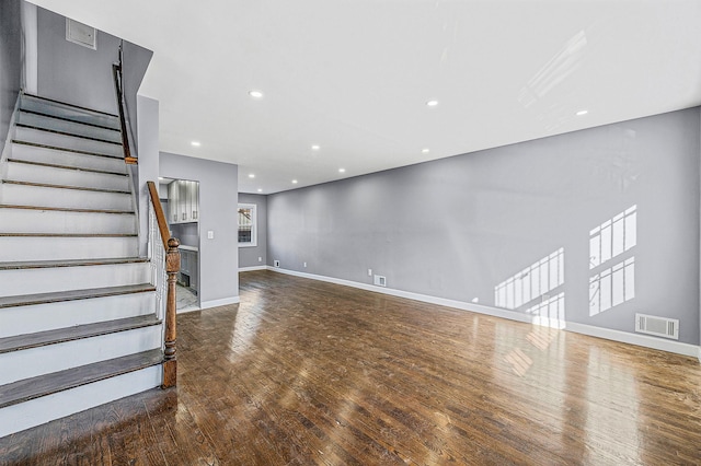 unfurnished living room with stairway, wood finished floors, baseboards, visible vents, and recessed lighting