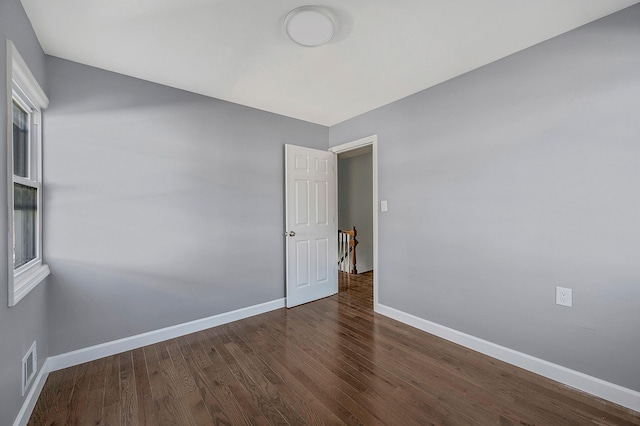 spare room featuring baseboards, wood finished floors, and visible vents