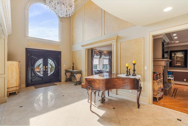 foyer featuring a towering ceiling, a baseboard radiator, recessed lighting, and a chandelier