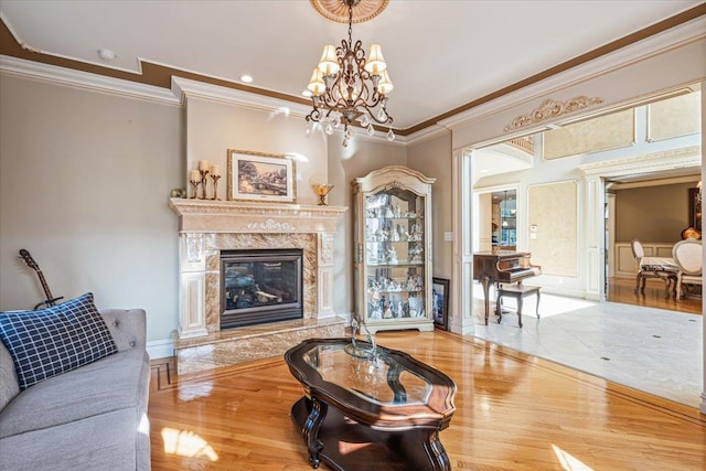 living room featuring crown molding, a notable chandelier, wood finished floors, and a high end fireplace