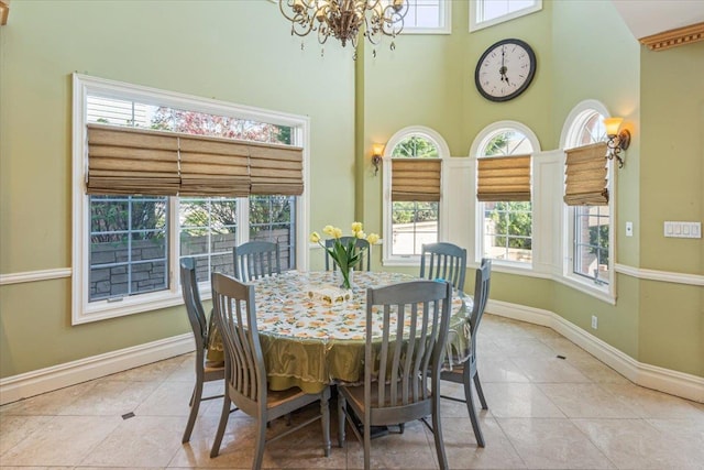 tiled dining room with baseboards, a notable chandelier, a high ceiling, and a wealth of natural light