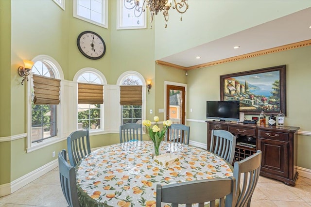 dining area featuring baseboards, a towering ceiling, a chandelier, and a wealth of natural light