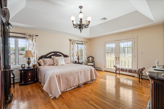 bedroom with visible vents, a notable chandelier, a tray ceiling, and multiple windows