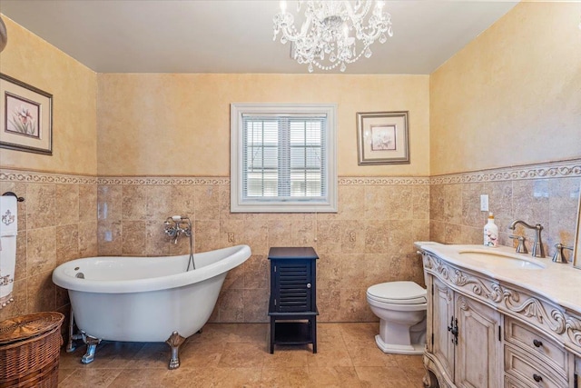 full bath featuring vanity, toilet, a chandelier, a freestanding tub, and tile walls