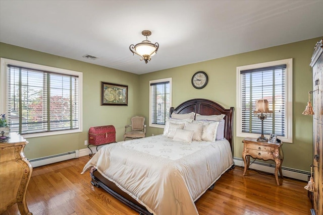 bedroom with visible vents, baseboards, wood finished floors, and baseboard heating