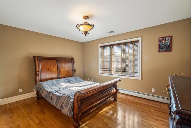 bedroom with visible vents, light wood-style flooring, baseboards, and baseboard heating