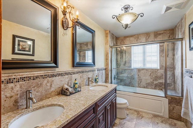 full bathroom featuring shower / bath combination with glass door, visible vents, a sink, and tile walls