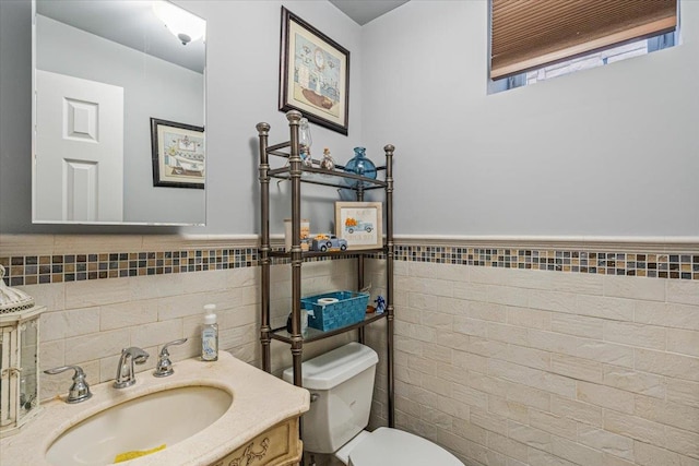 bathroom featuring tile walls, a wainscoted wall, vanity, and toilet