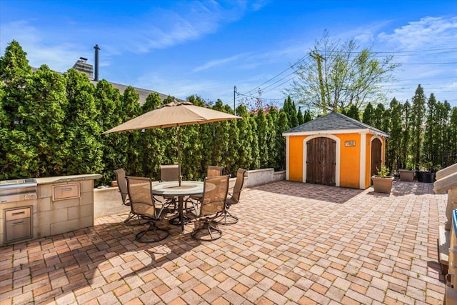 view of patio / terrace featuring an outdoor structure, outdoor dining area, a storage shed, and an outdoor kitchen