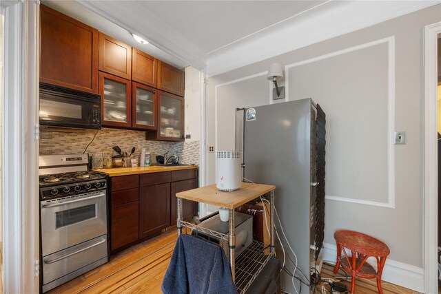 kitchen with tasteful backsplash, glass insert cabinets, stainless steel appliances, baseboards, and light wood finished floors
