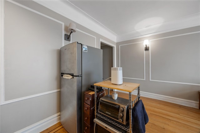 interior space featuring baseboards, wood finished floors, and freestanding refrigerator