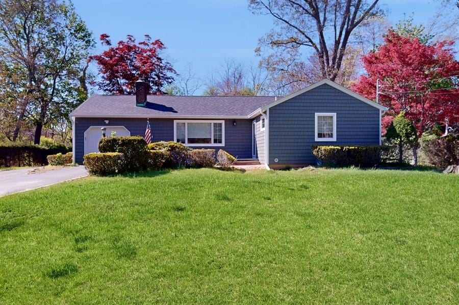 89 Christian Ave, Stony Brook, NY 11790 - ranch-style home with a chimney, roof with shingles, a front yard, a garage, and aphalt driveway