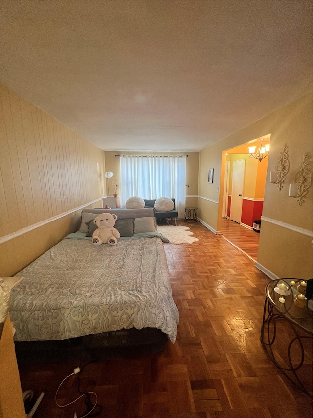 bedroom featuring wood walls, baseboards, and a chandelier