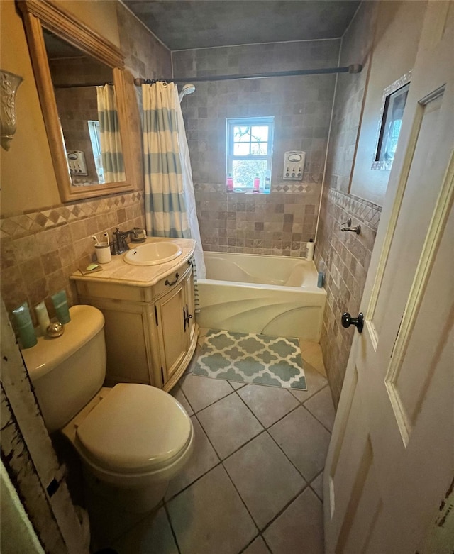 full bath featuring tile patterned floors, toilet, vanity, tile walls, and shower / bath combo with shower curtain