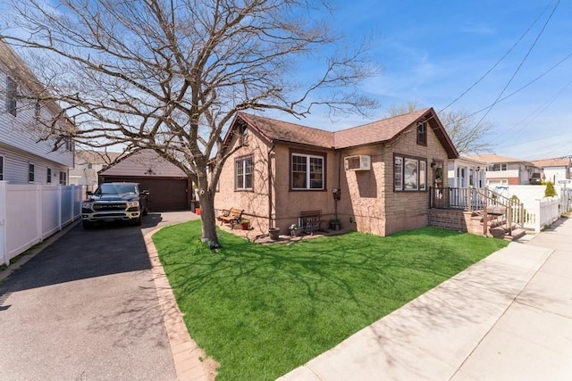 view of front of property with fence, a front yard, an AC wall unit, and a garage